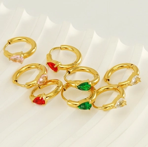Détail de créoles dorées ornées de zircons roses, verts et rouges en forme de goutte d'eau
