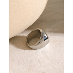 Macro view of minimalist thick silver stainless steel spiral ring on a textured surface