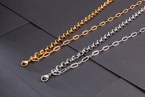 Detail of gold and silver double-layer stainless steel necklaces on black texture