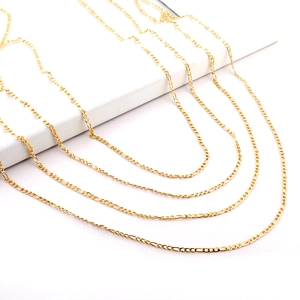 Detail of four golden Figaro chains in various lengths made of polished stainless steel