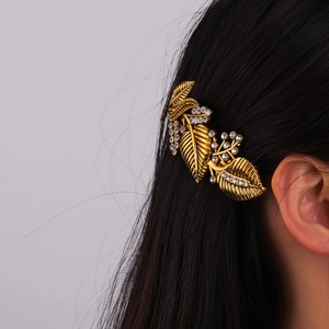 Vintage gold leaf hair clip with rhinestones shown on black hair from a side view
