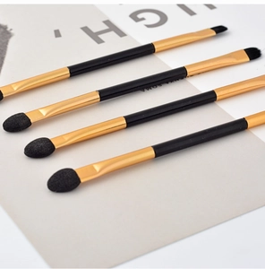 Macro detail of double-ended eyeshadow brush with gold aluminum ferrule and black handle