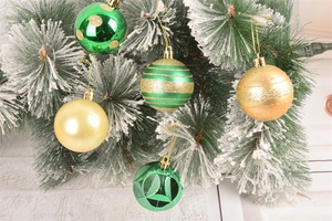 Detail of green and gold Christmas ornaments with glitter stripes on snowy pine branches
