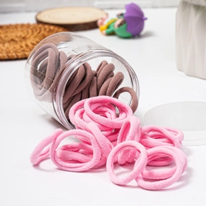 Detailed macro view of pink and brown towel fabric hair ties spilling from a storage jar