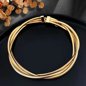 Detailed view of golden multi-layer snake chain necklace on a black decorative tray