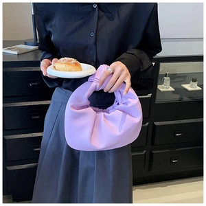 Close-up of lilac purple pleated handbag featuring a unique knotted handle design