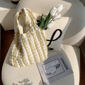 Close-up of yellow and white bubble textured fabric tote bag on a cozy white sofa
