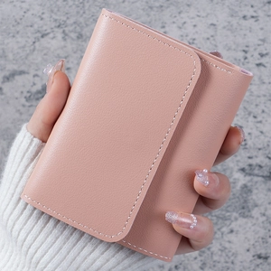 Close-up of small pink leather wallet with white stitching held in hand