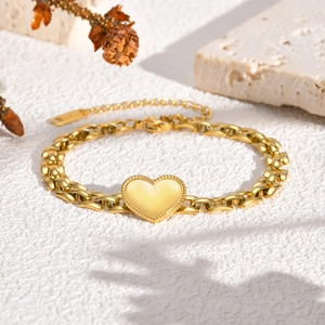 Golden stainless steel heart bracelet featuring flat link chain on textured background