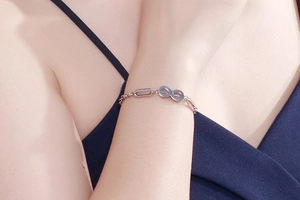 Close-up of a silver infinity charm chain bracelet worn on a woman's wrist