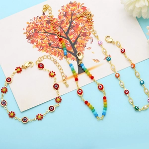 Detail of bohemian gold chains featuring colorful evil eye beads and enamel flowers
