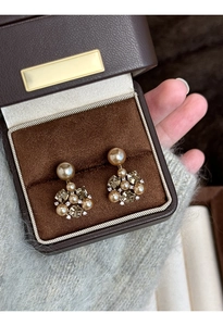 Close-up of champagne gold pearl and crystal flower earrings in a velvet jewelry box