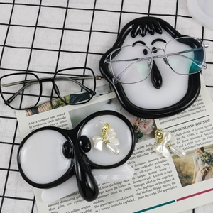 Close-up of resin storage trays showing eyeglass frames and pearl bow earrings details