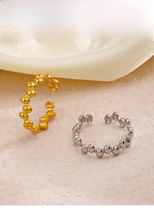 Macro shot of gold and silver beaded open rings on soft silk fabric background