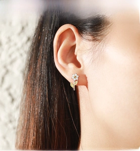 Dettaglio orecchino a fiore in argento S925 con petali bianchi e gemme gialle lucide