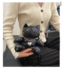 Detail of black cat doll crossbody bag featuring silver metal studs and chunky chain strap