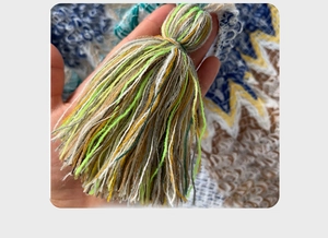 Close-up of handmade colorful yarn tassels in green and yellow for ethnic travel shawls