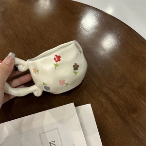 Detailed close-up of a French irregular ceramic coffee cup with hand-painted floral patterns
