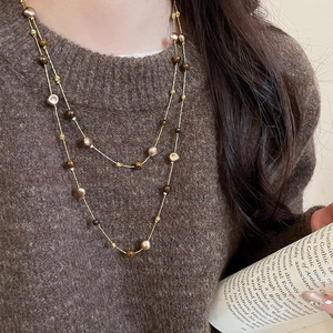 Detail of vintage tiger eye beaded necklace layered on a brown knit sweater