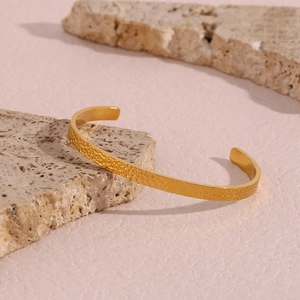 Macro detail of 18K gold plated hammered texture surface on a stainless steel cuff