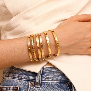 Detail of gold-plated stainless steel bangles with star engravings and cubic zirconia