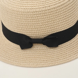 Close-up of natural beige straw hat featuring detailed weave and black ribbon bow