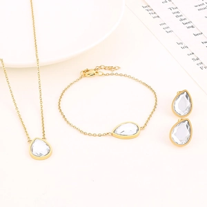 Gros plan d'un ensemble de bijoux dorés avec zircons en goutte sur un plateau blanc