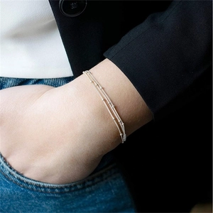 Close-up of minimalist multi-layer silver bead bracelet on a model wearing a suit