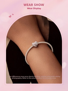 Close-up of a silver mesh chain bracelet with a pink floral heart charm on a wrist