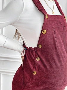 Detail of burgundy corduroy maternity overalls featuring side buttons and soft texture