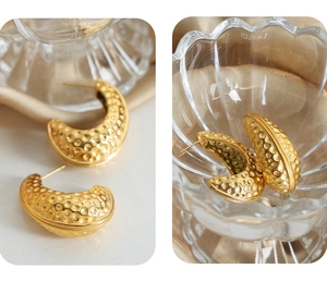 Macro detail of golden retro C-shape earrings featuring textured hammered metal craftsmanship