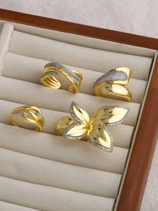 Detailed view of four 18k gold plated adjustable rings with floral and geometric designs