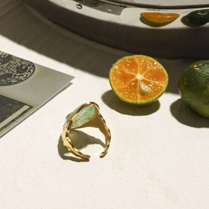Detail of a vintage golden textured ring with a green marble stone on a stone surface