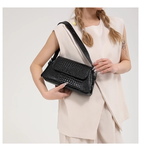 Close-up of black crocodile pattern PU shoulder bag worn by a model in studio