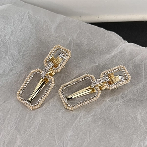 Macro view of gold alloy hair clips featuring pearl and rhinestone encrusted rectangles