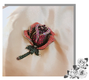 Close-up of vintage rose brooch with red rhinestones and detailed metallic floral textures