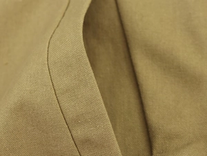 Close-up detail of khaki linen blend fabric texture and stitching on blazer jacket
