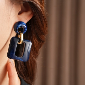 Detail of geometric blue marble resin earrings with gold metal link worn by model