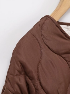 Close-up of quilted brown puffer jacket featuring fine stitching and round neckline details