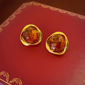 Close-up of golden irregular metal frame with amber resin stone in a French retro style