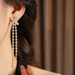 Primo piano di una modella che indossa orecchini a farfalla in oro 18K con zirconi