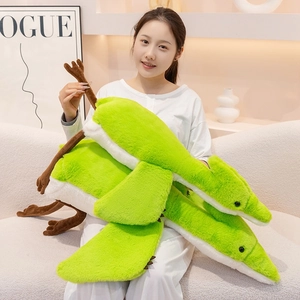 Detailed view of large green plush pterodactyl toys on a cozy home sofa setting