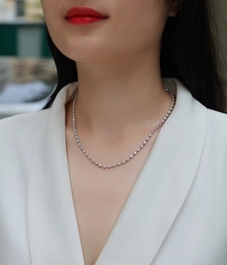 Close-up of S925 sterling silver moissanite chain necklace on a model wearing a white suit