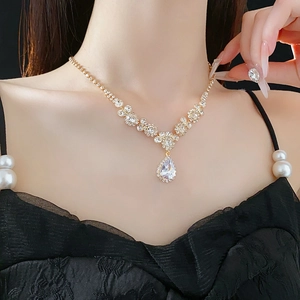 Détail du collier goutte en zircon plaqué or porté par un mannequin sur fond noir élégant