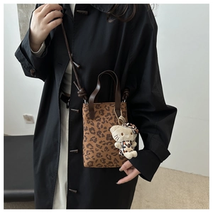Leopard print canvas crossbody bag with twin handles and cute character plush charm