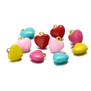 Macro shot of colorful enamel heart charms with gold loops for DIY jewelry making