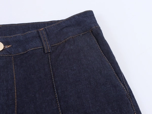 Dettaglio ravvicinato della vita dei jeans blu scuro con bottone dorato e cuciture