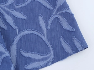 Gros plan sur le tissu denim jacquard bleu avec motifs feuilles et bords effilochés