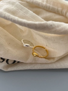 Detailed view of silver and gold beaded rings resting on a beige linen jewelry pouch