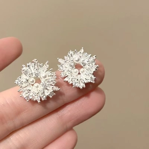 Detailed macro view of silver flower earrings featuring sparkling zircons and delicate pearls